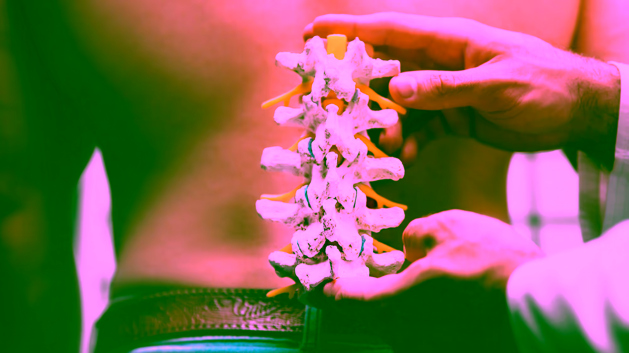 Ein Orthopäde hält ein Wirbelsäulenmodell vor den Rücken eines Patienten mit einem Bandscheibenvorfall.